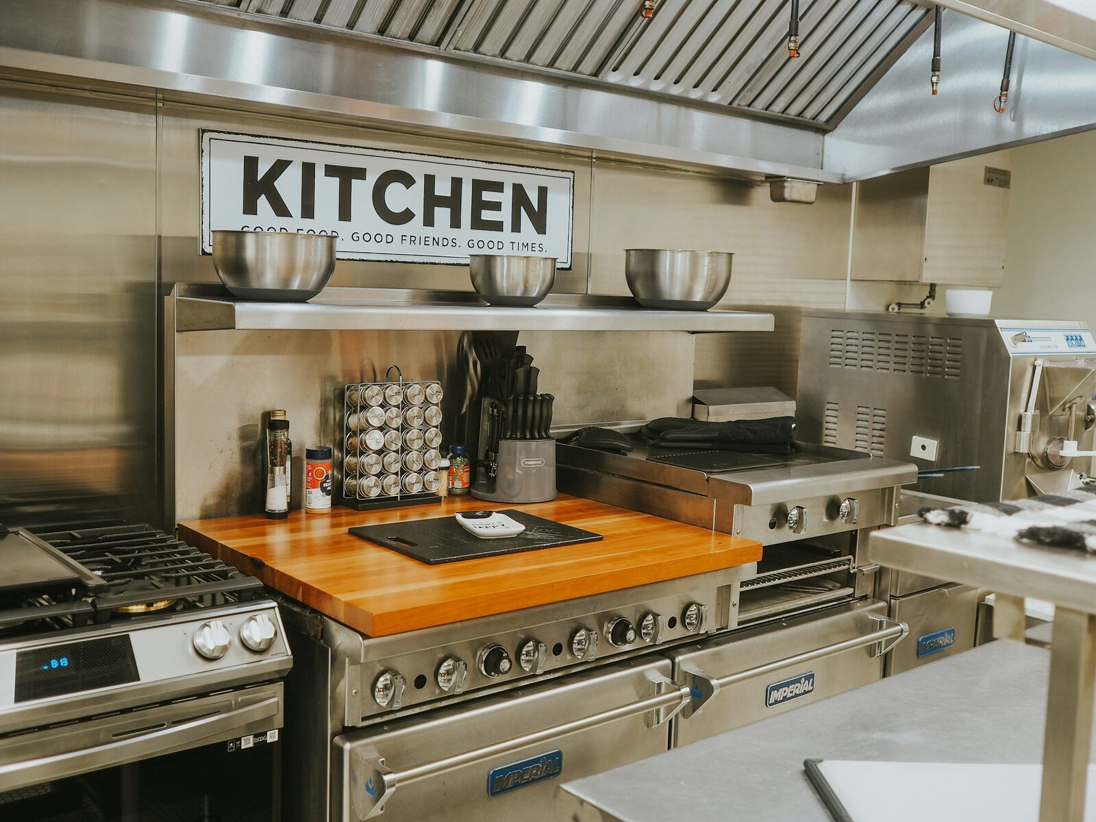 A stainless steel commercial cooking range with griddle and extractor hood in a professional kitchen