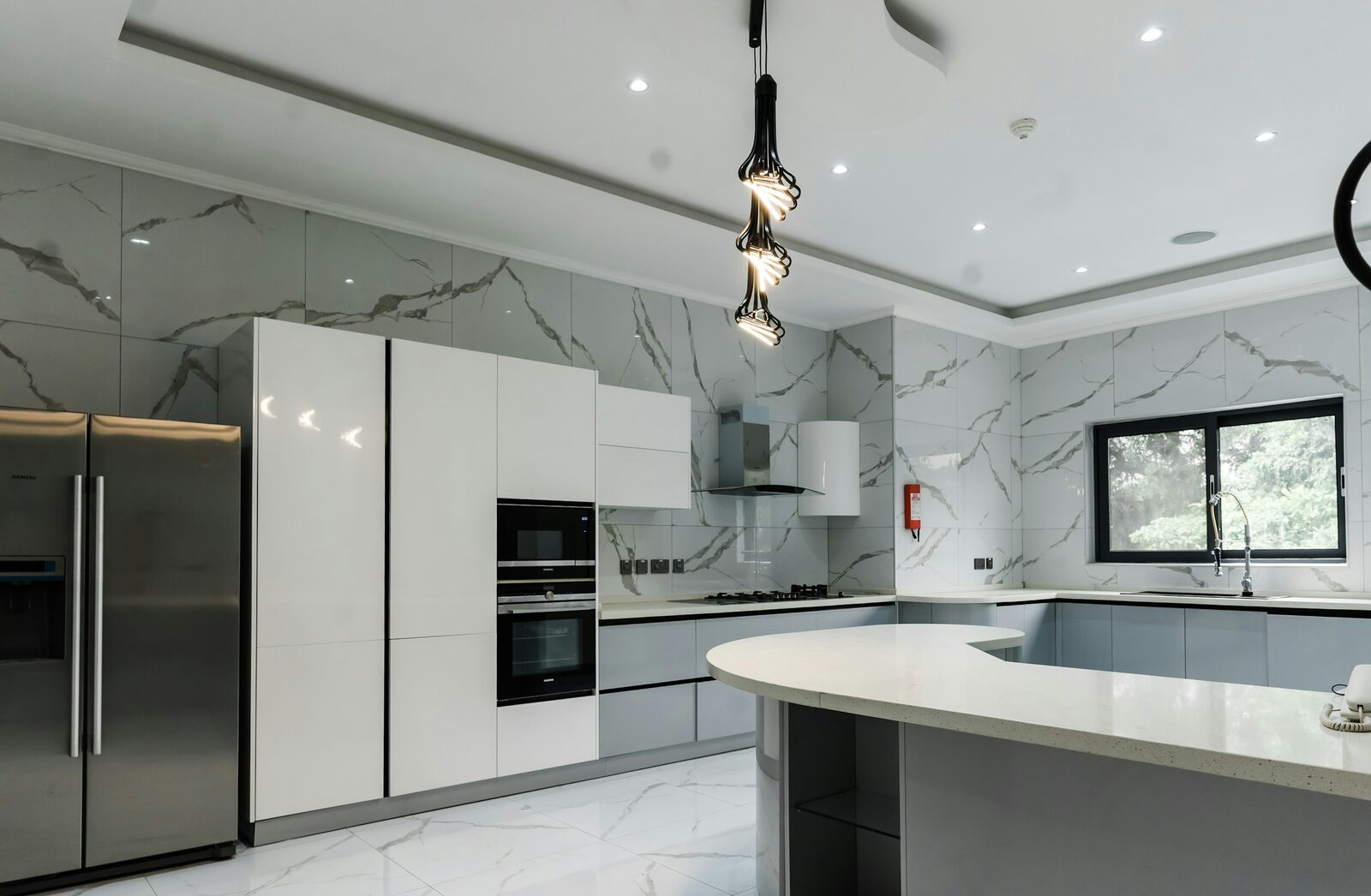 A modern kitchen with a stainless steel gas range, oven, extractor hood and refrigerator